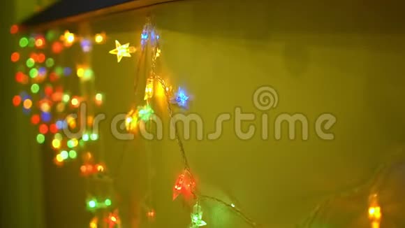多色圣诞假日花环和黄色墙壁背景上的灯光视频的预览图