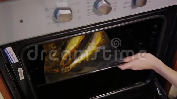 用烤炉里烤的腌料煮整条烤鱼女厨师把烤盘和生鱼放进热烤箱里视频的预览图