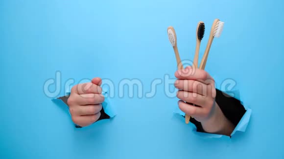 不可辨认的女性做拇指向上的手势展示竹子生态牙刷手势通过撕纸蓝色背景视频的预览图