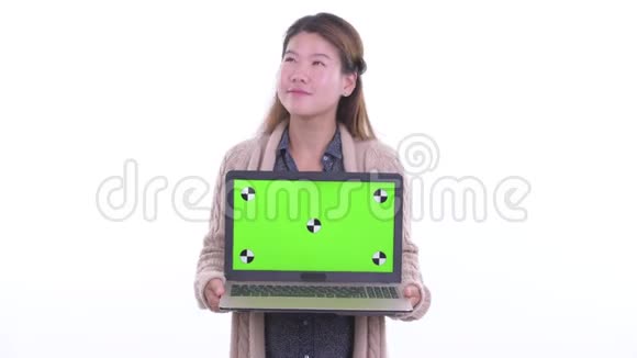 快乐的年轻亚洲女人一边思考一边展示准备过冬的笔记本电脑视频的预览图