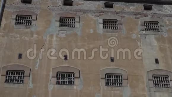 监狱建筑的旧石墙有小窗户和栏杆视频的预览图