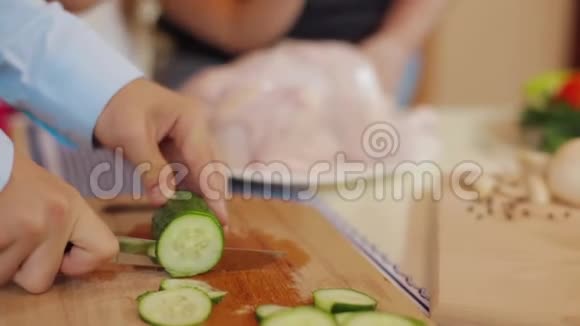 儿子切新鲜黄瓜菜一起在厨房做菜父母教有趣的孩子帮忙视频的预览图