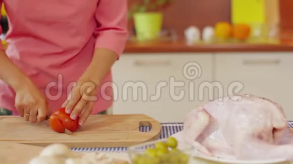 在餐桌上用健康食品做沙拉的木切割板上切番茄肉的特写镜头视频的预览图