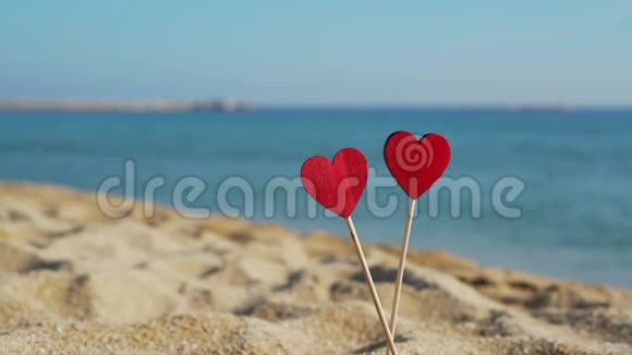 在沙滩上的沙滩上两颗美丽的木制心在大海的背景上视频的预览图