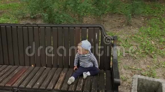 小男孩在公园的长凳上爬行视频的预览图