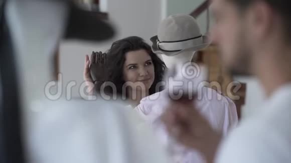 布吕内特的女人温柔地抚摸着戴在帽子里的男模特的手而男人则在前台喝酒视频的预览图