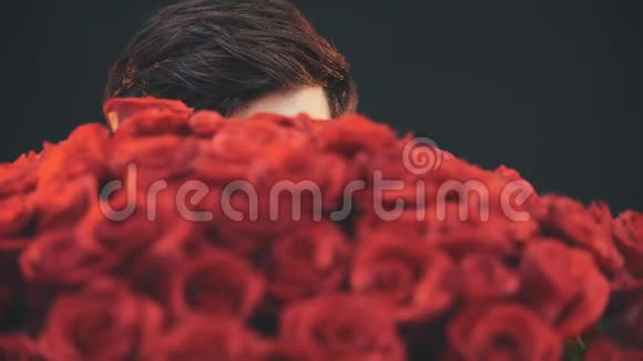 年轻人看着一大束红色玫瑰有着善良的眼睛视频的预览图