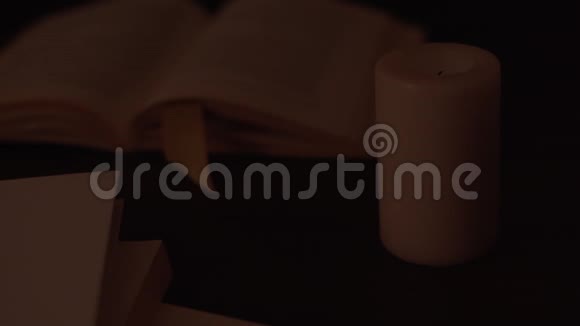 合上一支蜡烛在微光下被照亮的镜头一个女人手在书页上翻页视频的预览图