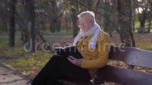 老年时戴眼镜手里拿着笔记本和铅笔的退休老人坐在长凳上计划着什么视频的预览图