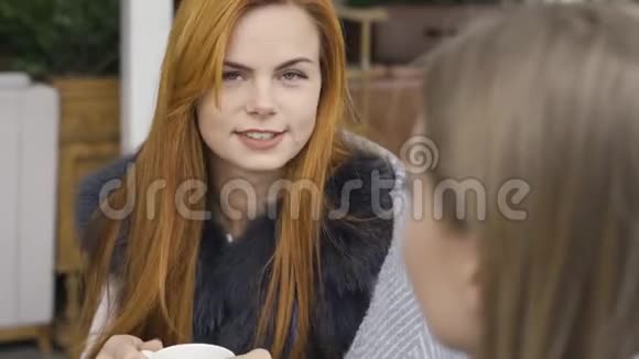 两个可爱的白种人女朋友盖着毯子坐在咖啡馆里聊天喝热茶青年妇女视频的预览图