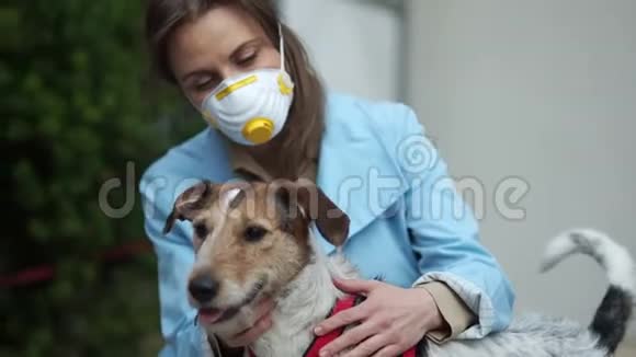 戴着医用口罩的年轻女子和她的狗坐在一起冠状病毒概念covid19视频的预览图