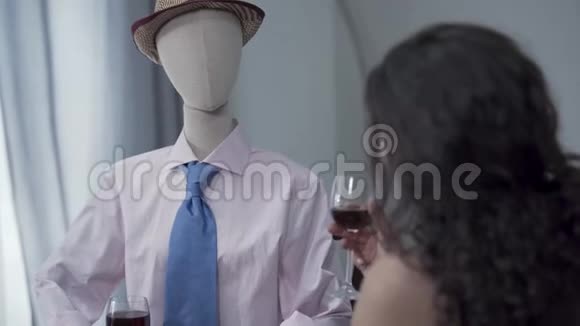 可爱的卷曲女人坐在桌子旁喝红酒帽子里戴着一个男模特模仿约会视频的预览图