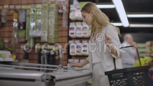 超市里的女孩从冰箱里拿出冷冻食品读一读产品的组成然后把它放好视频的预览图