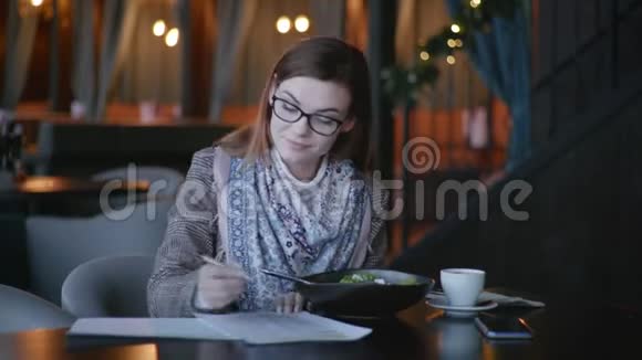 漂亮的带眼镜的年轻女性喜欢适当营养的人正在餐馆吃午餐检查卡路里含量视频的预览图