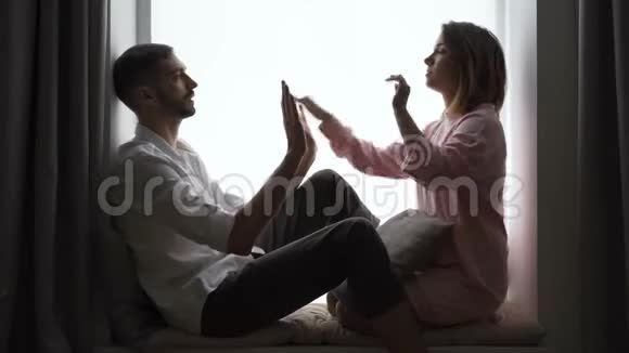 可爱的一对夫妇坐在窗台上玩拍子蛋糕夫妻在家休息室内休闲视频的预览图