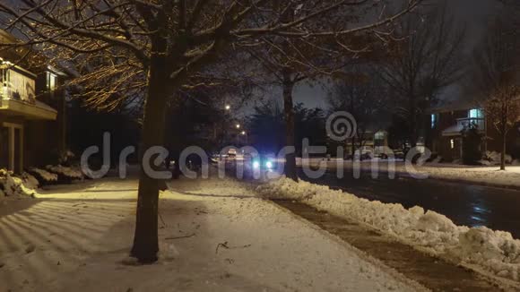 汽车开得很慢夜间在住宅区的街道上积雪覆盖视频的预览图