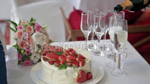 桌子上摆着一个草莓蛋糕和心蛋糕一个新娘花束装饰包装上的香槟瓶视频的预览图