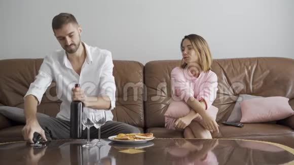 英俊的男人用开瓶器打开酒瓶而他的妻子坐在附近幸福的夫妻浪漫的晚餐视频的预览图