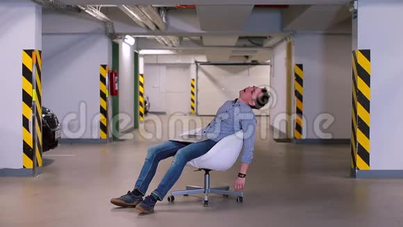 一个男人在办公室地下车库的椅子上醒来视频的预览图