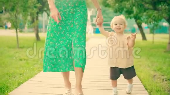 微笑的女婴和她的妈妈走在公园的小路上视频的预览图