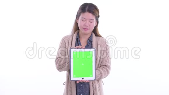 快乐的年轻亚洲女人一边思考一边展示准备过冬的数码平板电脑视频的预览图