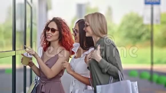 三位时尚女朋友带着购物袋想看看玻璃窗视频的预览图