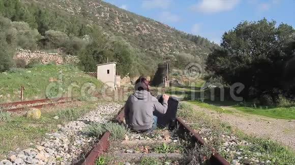 女人坐着站起来一个走在废弃的铁路轨道中间的女人带着她的手提箱视频的预览图