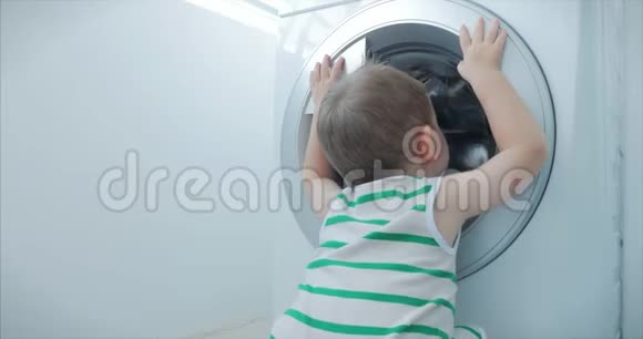 可爱的小男孩看着洗衣机里气缸旋压机工业概念洗衣机视频的预览图