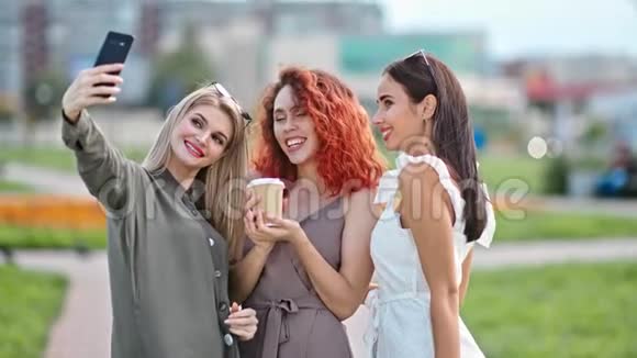 可爱的微笑性感的年轻女人用智能手机摆姿势自拍视频的预览图