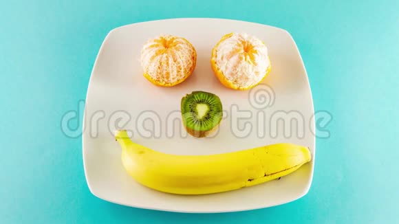 橘子猕猴桃和一根香蕉放在白色盘子里就像人类的笑脸视频的预览图