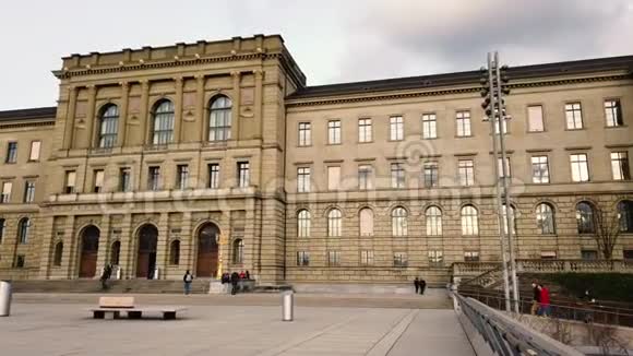 瑞士苏黎世大学ETHUniversity苏黎世市傍晚时分人们穿过框架在市中心的老主楼上空盘旋视频的预览图