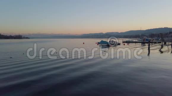 瑞士苏黎世市日落后湖畔长廊的景色覆盖了在背景中轻轻移动的水山上的船只视频的预览图