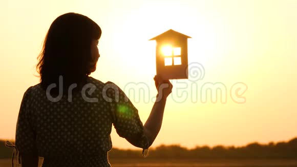 日落时分一个女孩的剪影她带着一个模特回家太阳光线穿过纸房的窗户这就是视频的预览图