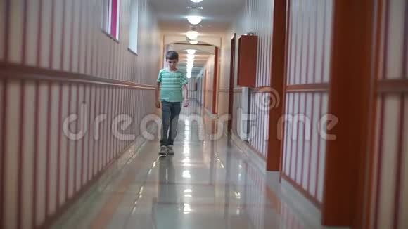 一个男孩正沿着一所教育机构的一条长长的走廊走着视频的预览图