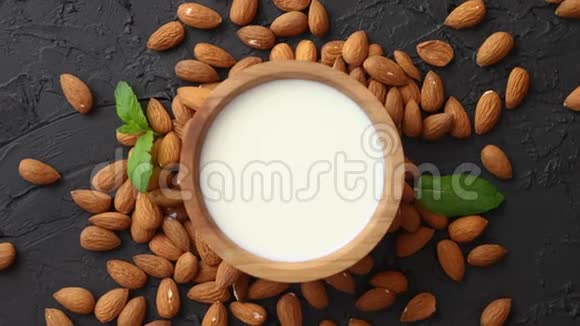 木碗中的鲜杏仁奶和黑石背景上的杏仁视频的预览图