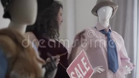 可爱的女孩跳舞与红色标志说出售在独家服装商店现代人体模型附近的女人视频的预览图