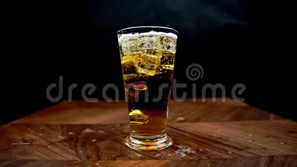 冰慢慢地掉进啤酒杯里啤酒溅到桌子上视频的预览图