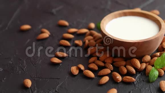 木碗中的鲜杏仁奶和黑石背景上的杏仁视频的预览图