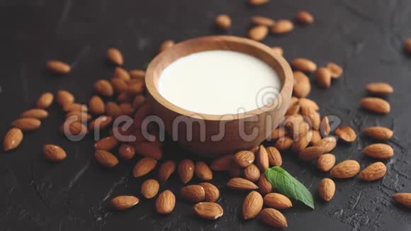 杏仁种子和一碗新鲜天然牛奶放在黑石背景上视频的预览图