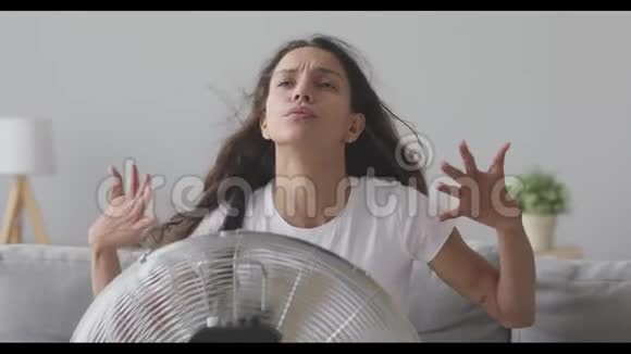 过热的年轻混血女孩坐在呼吸机前面视频的预览图
