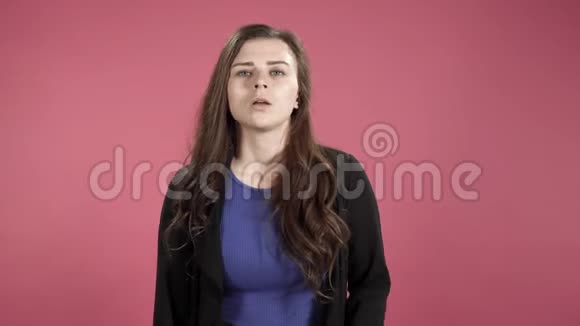 沮丧的年轻女子手臂交叉在她的胸部与粉红色的背景视频的预览图