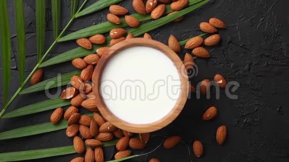 杏仁种子和一碗新鲜天然牛奶放在黑石背景上视频的预览图