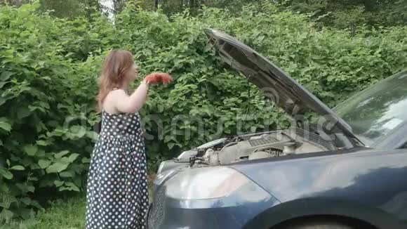 穿着斑点裙子的女孩关上汽车罩满意地微笑着侧视视频的预览图