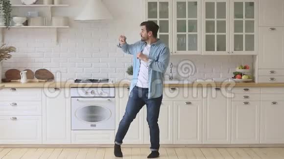 活泼无忧无虑的年轻人站在厨房里享受滑稽的舞蹈视频的预览图
