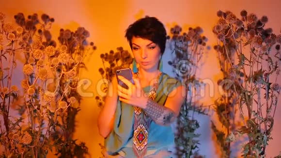 一个女孩在野生多刺植物的智能手机上摆姿势和拍照视频的预览图