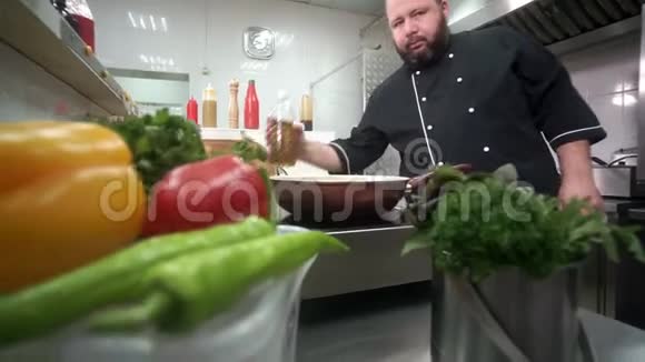 作为一名男性厨师的特写镜头将油倒入煎锅中前景绿色蔬菜视频的预览图