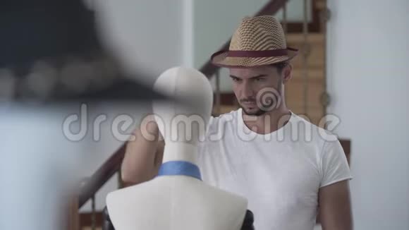 肖像英俊的胡须男把帽子戴在人体模型的头上他在缝纫室玩得很开心视频的预览图
