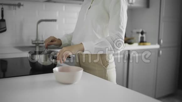 煮燕麦片一个女人把煮好的粥倒在盘子里特写早餐视频的预览图