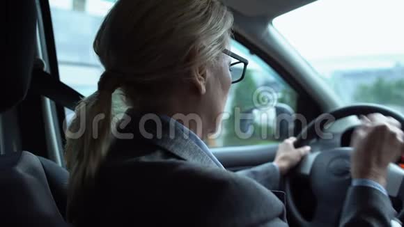 疲劳的女人按摩麻木的脖子坐在汽车的驾驶座上后视镜视频的预览图
