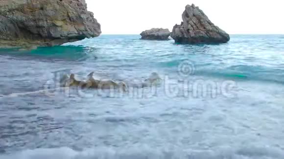 穿着花边裙子的女人光着脚慢慢地走在潮湿的沙滩上海浪冲刷着海岸视频的预览图